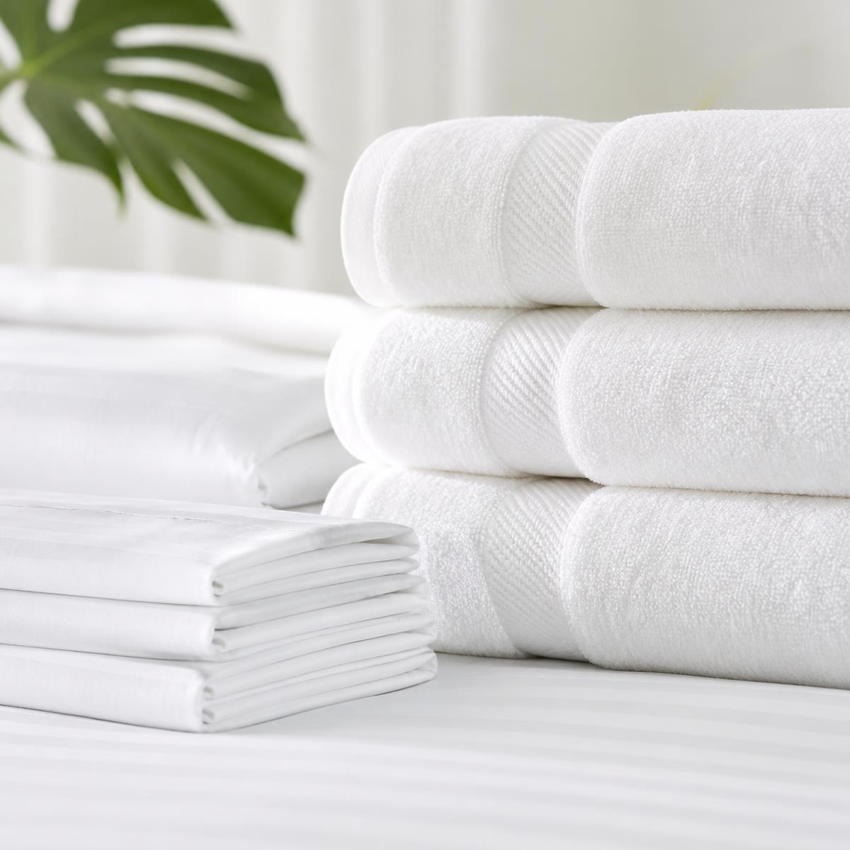 Toallas y sábanas blancas de hotel dobladas y apiladas